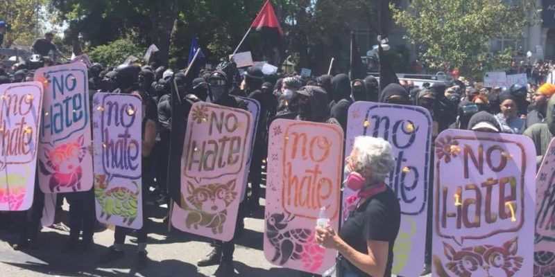 Black clad demonstrators with "NO HATE" signs