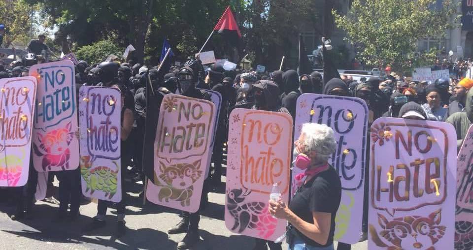 Black clad demonstrators with "NO HATE" signs