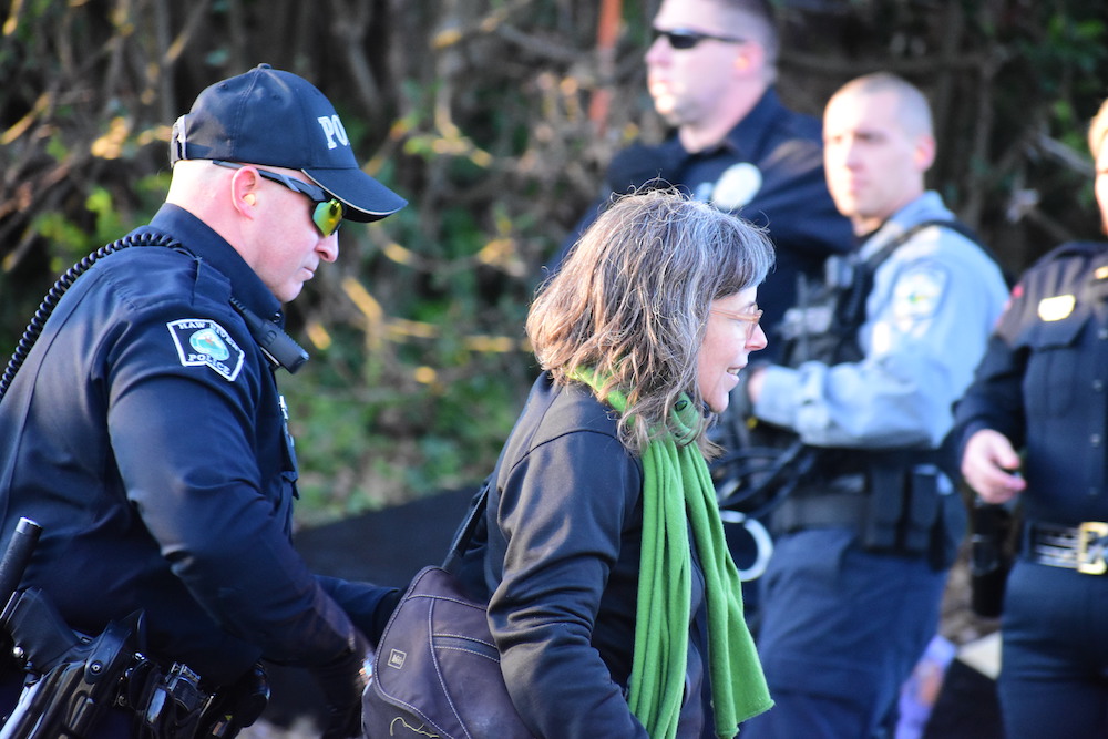 Police officer putting zip ties on a middle-aged white woman