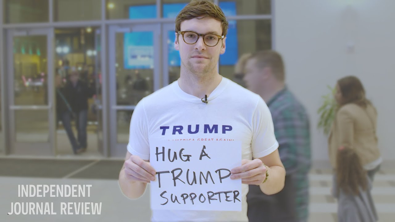 white man holding a sign that says "hug a Trump supporter"