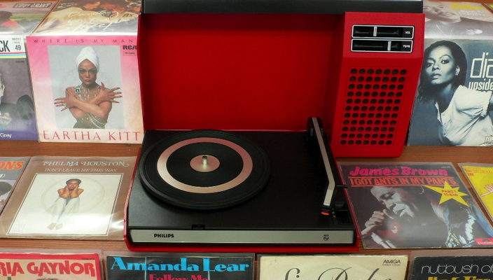 plastic record player surrounded by albums