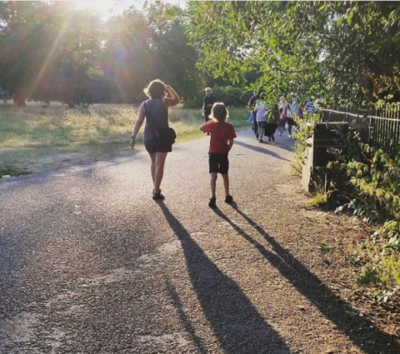 long shadows of a short curvy adult and a child walking in a London park